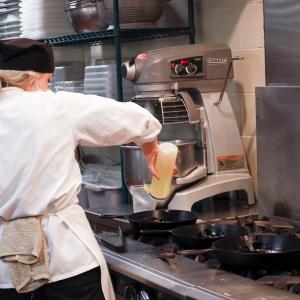 Culinary student working in kitchen by stove