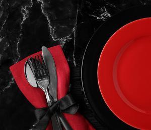 Black marbel table with red plate and napkin, set with silverware